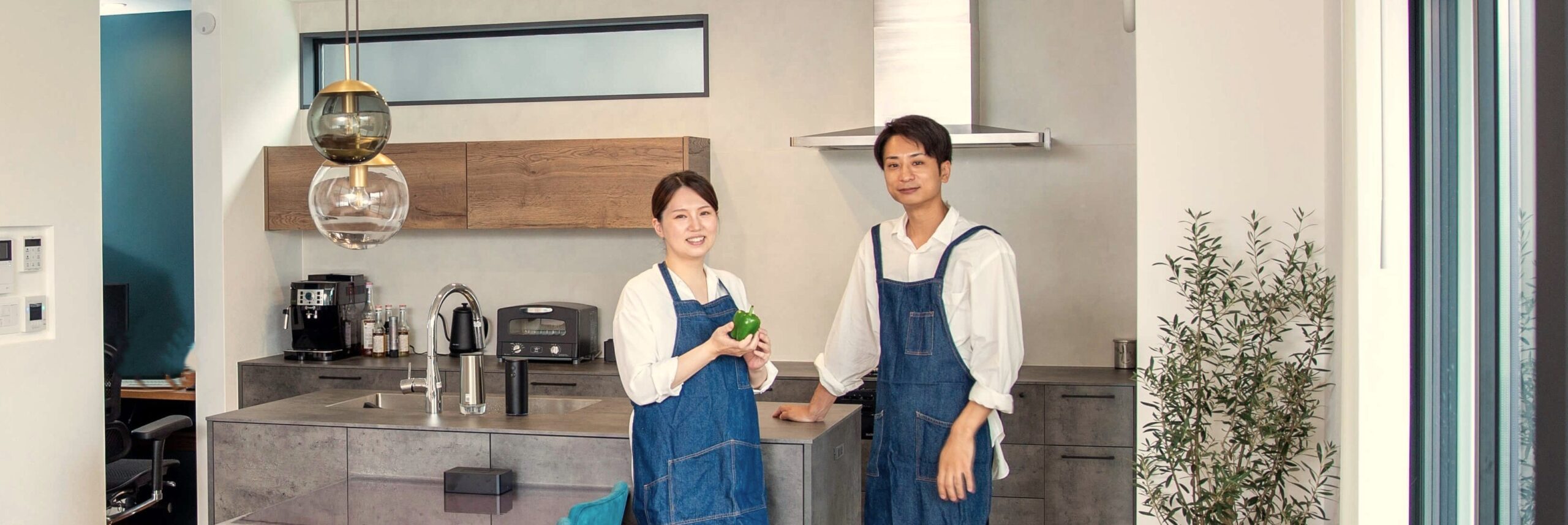 新しいキッチンの前でエプロン姿の夫婦が取材を受けている様子